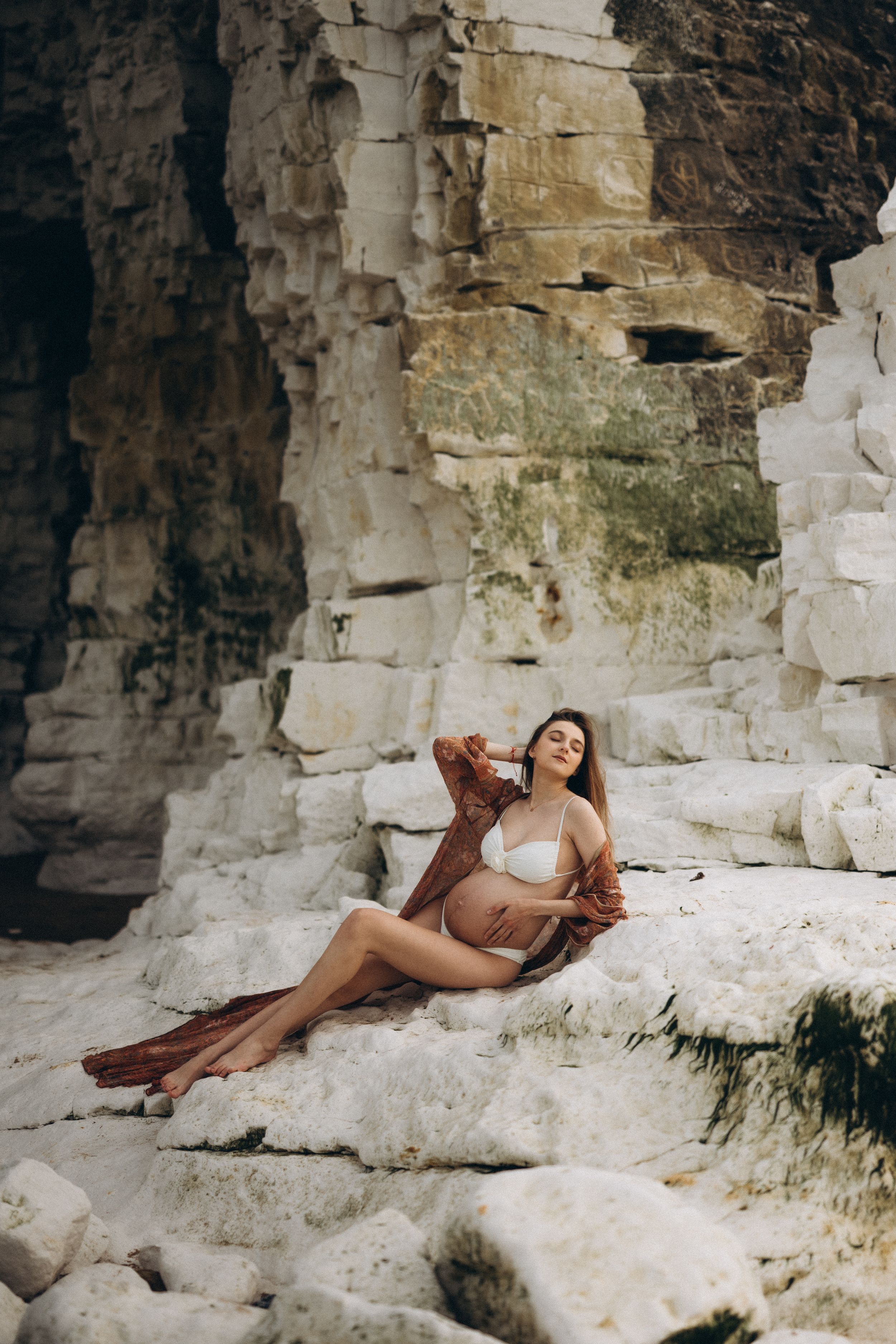 A pregnant woman laying down on the beach