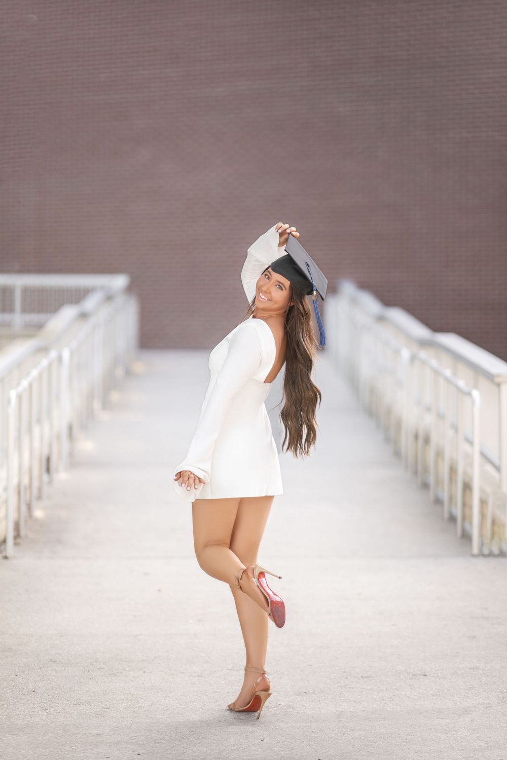 Stylish photo of someone in a white summer dress striking a playful pose on a concrete walkway with railings.