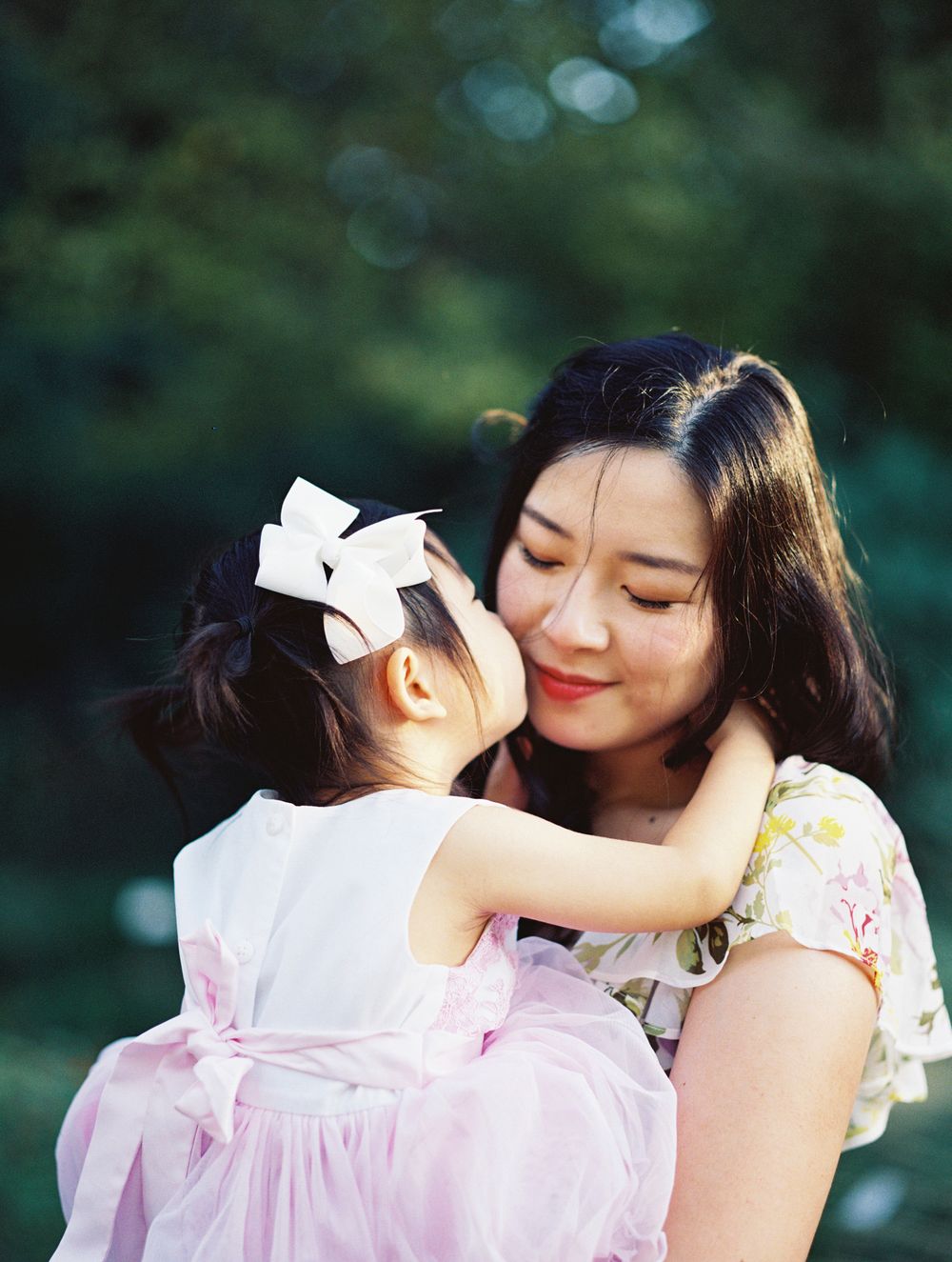 Tender moment shared in a lush garden setting with delicate floral attire.