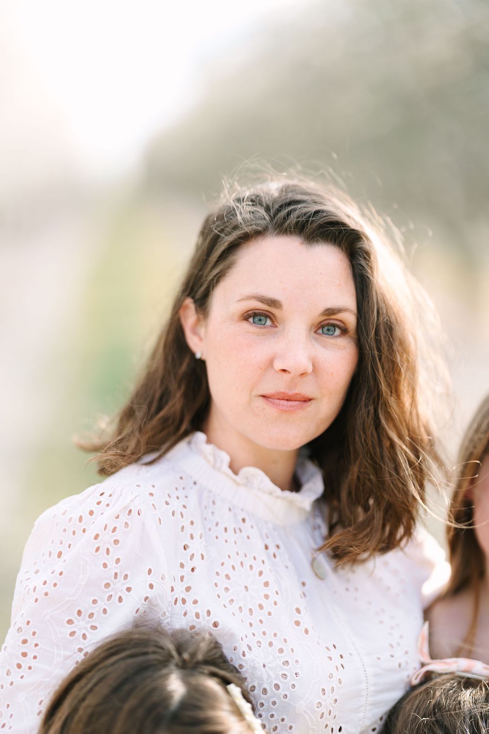Portrait in soft lighting wearing white eyelet lace top against dreamy background.
