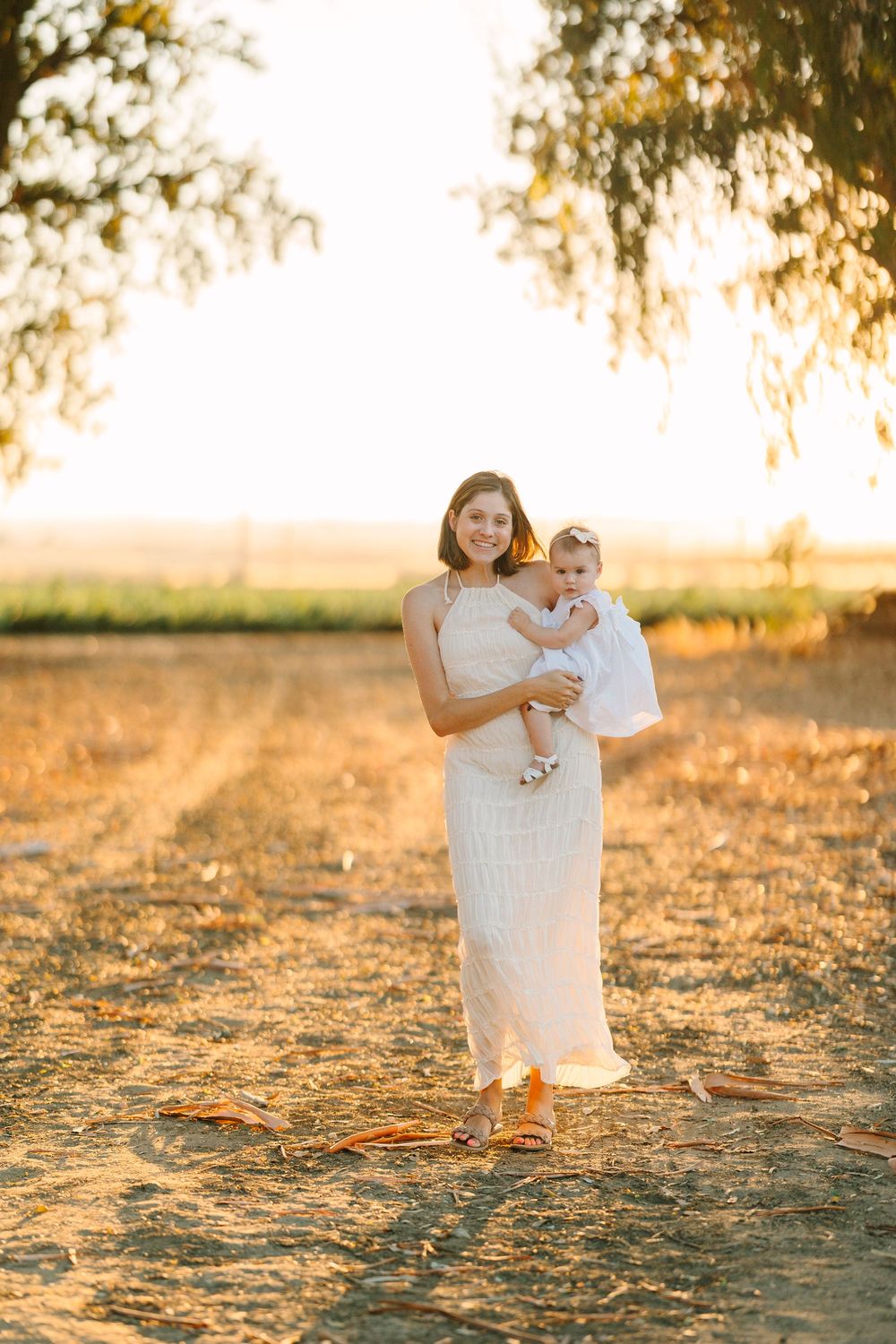 A sunset family portrait showing figures in white clothing standing in a golden field.