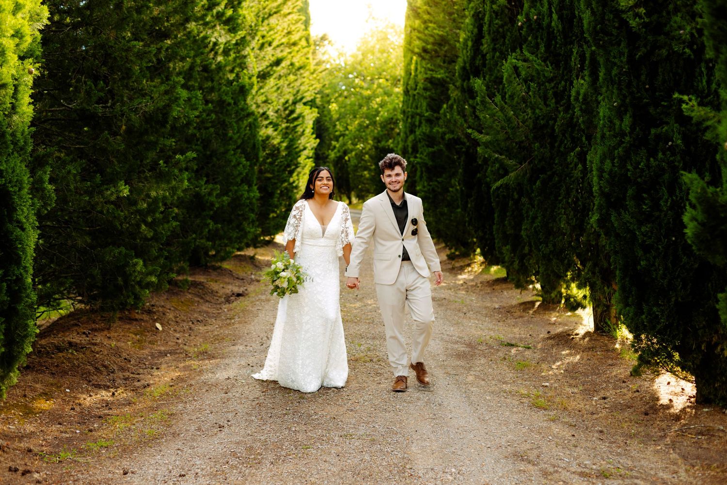 Tree-lined path at sunset with people walking in white attire.