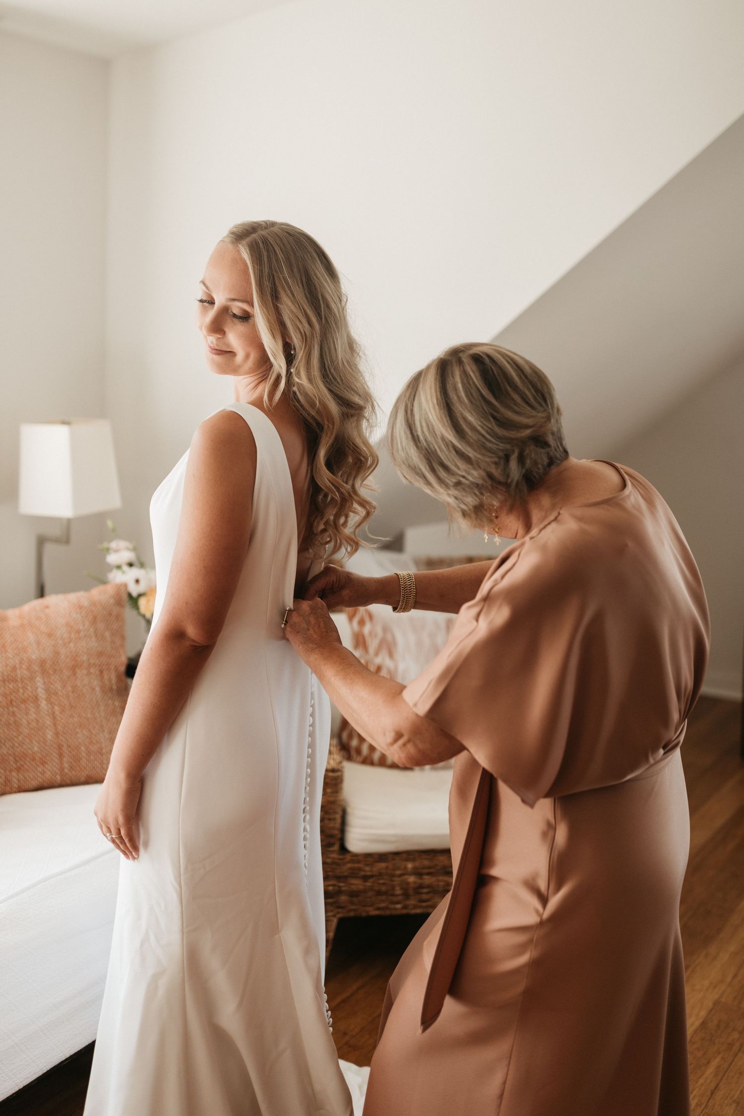 Final wedding dress adjustments being made in an elegant getting-ready room.