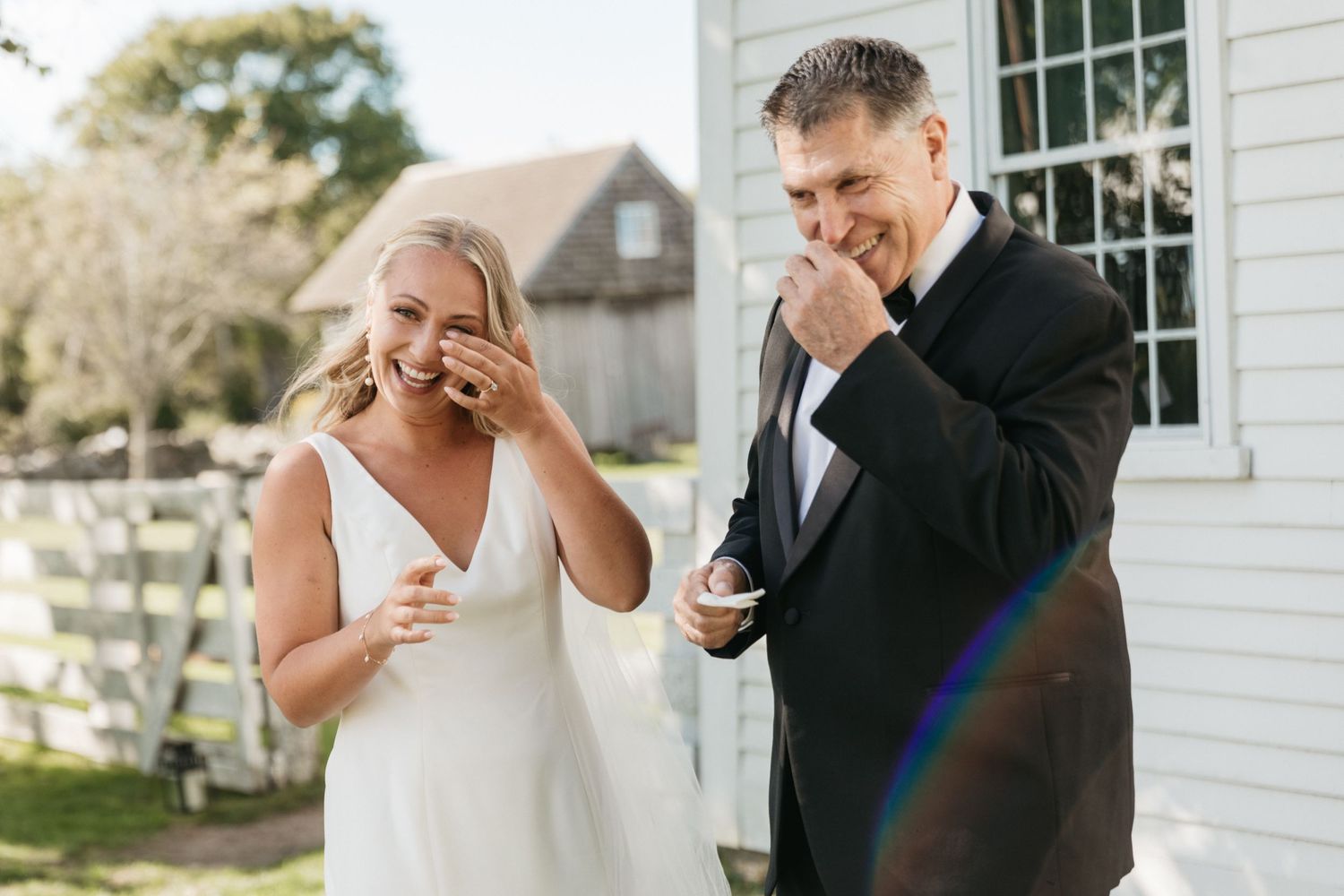 Wedding couple sharing emotional moment and laughing together outside white building.