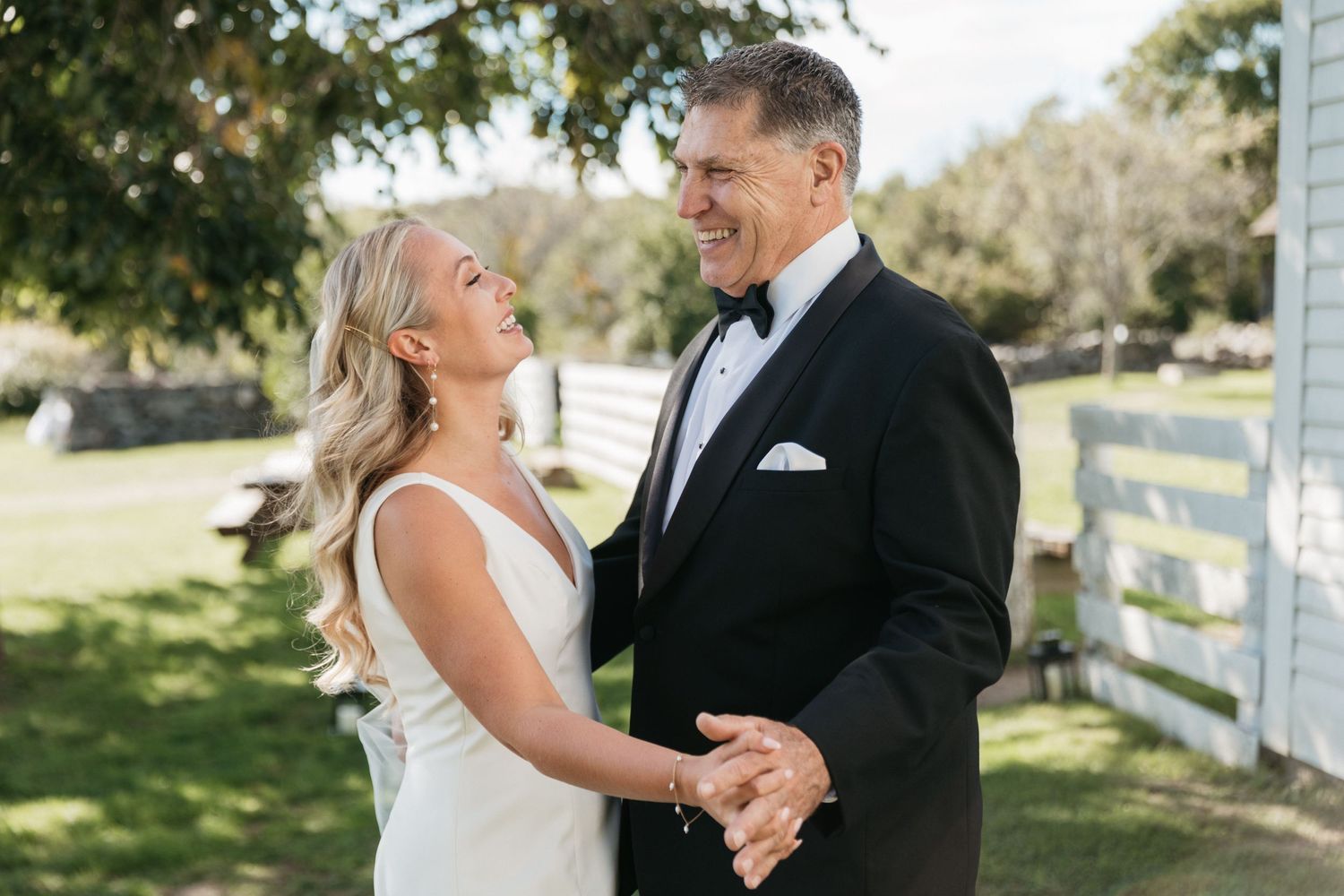 Couple sharing intimate moment during outdoor wedding ceremony by white fence.