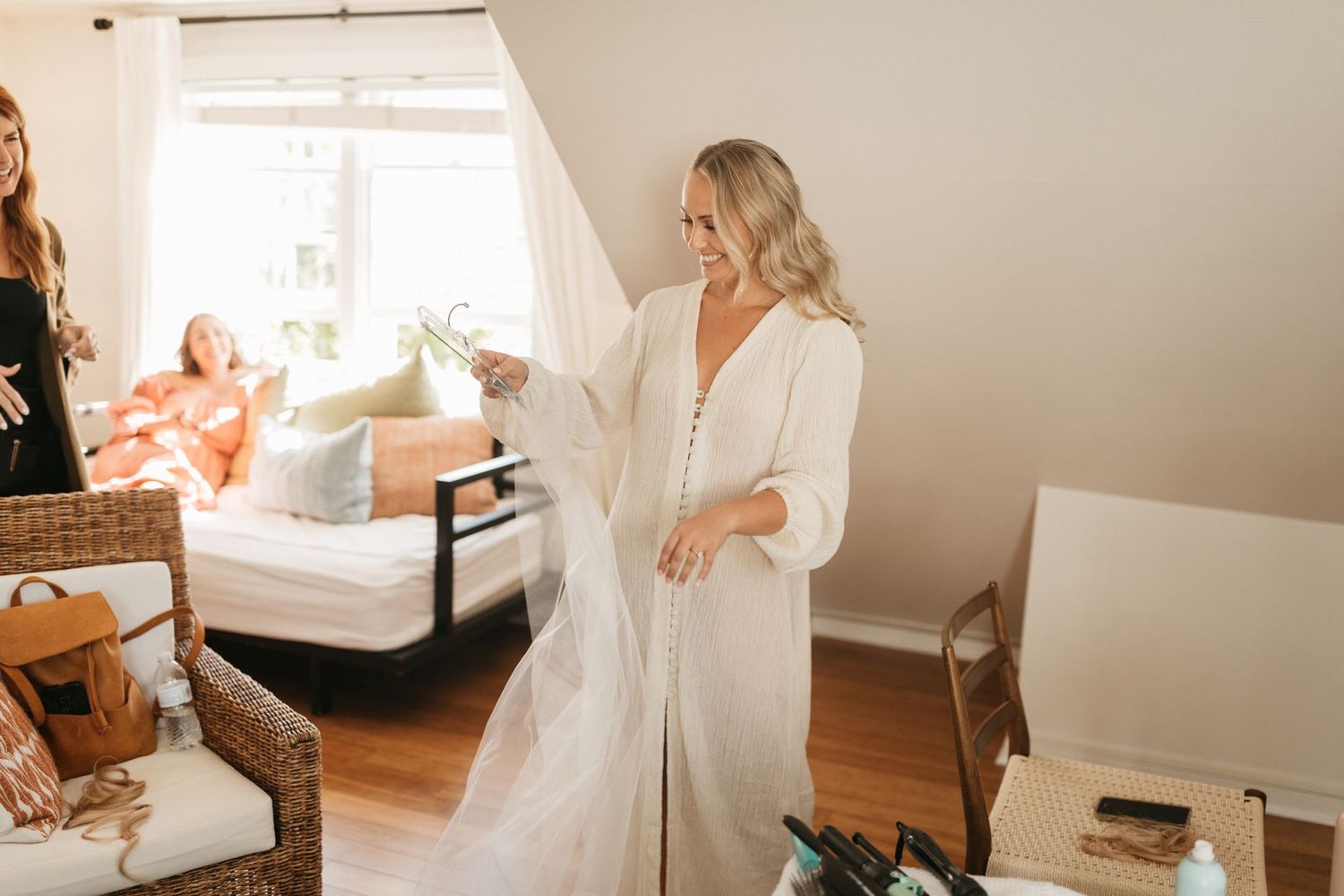Wedding preparation scene with white dress visible in bright, sunlit room.