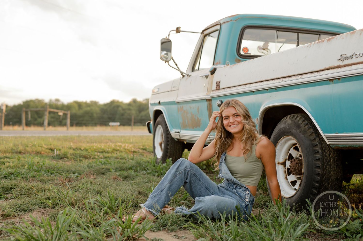 A casual portrait next to a classic turquoise and white pickup truck in a field.