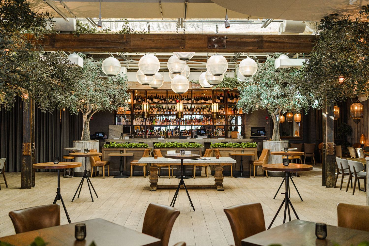Elegant event space with hanging lights, green decor and fully stocked bar.
