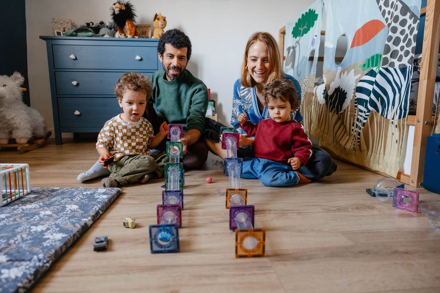 famille jouant au circuit de billes dans la chambre des enfants avec leur photographe de famille a Lille pour immortaliser ces instants