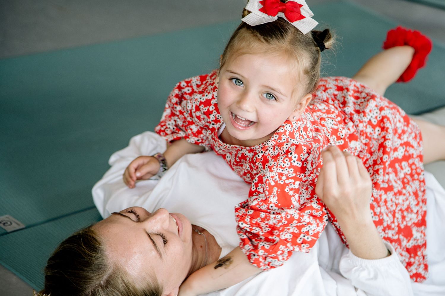 Parent and child share a playful moment during a dance activity on a soft mat.