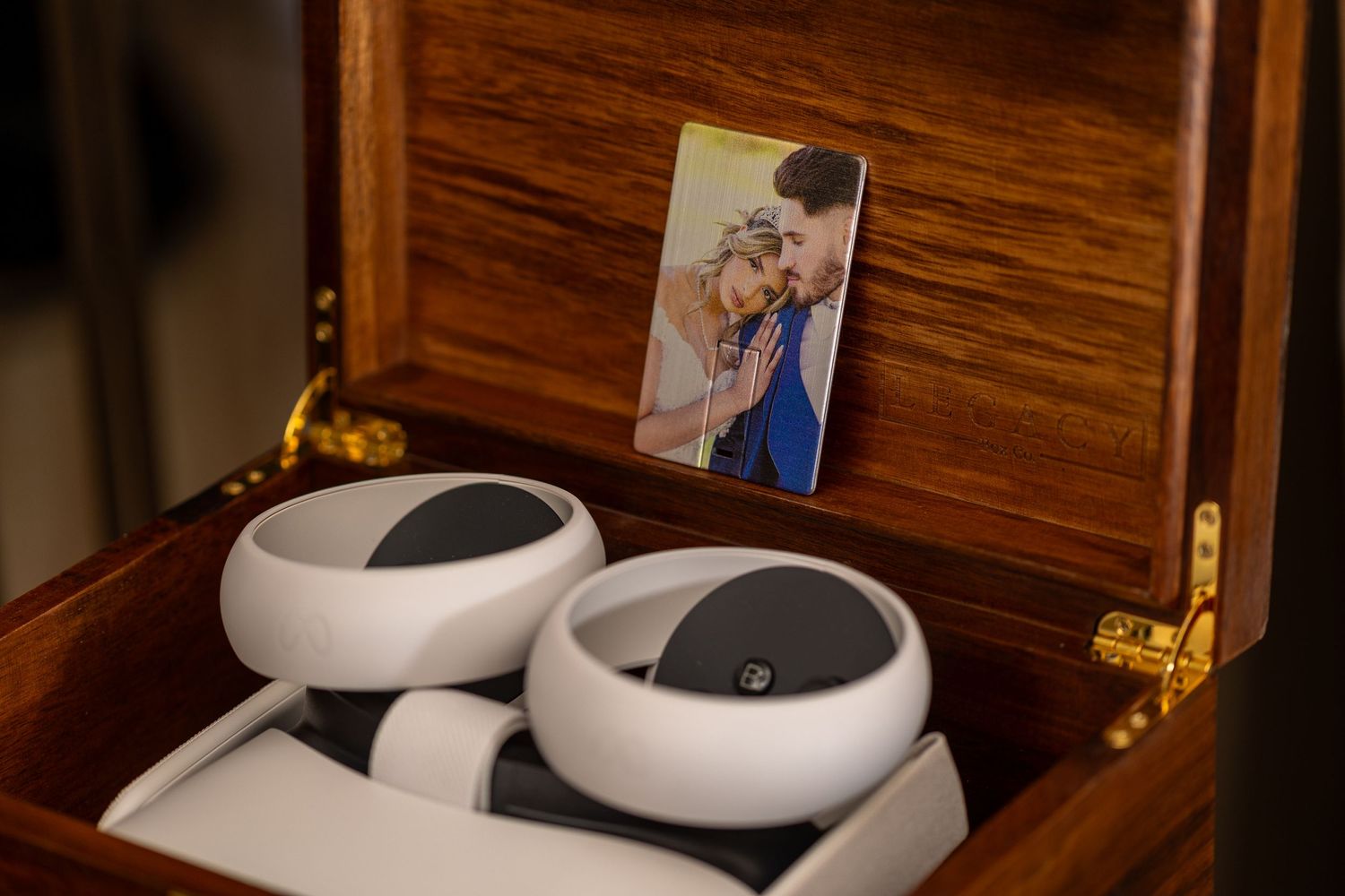 An open wooden box containing white electronic devices and a mounted photograph.