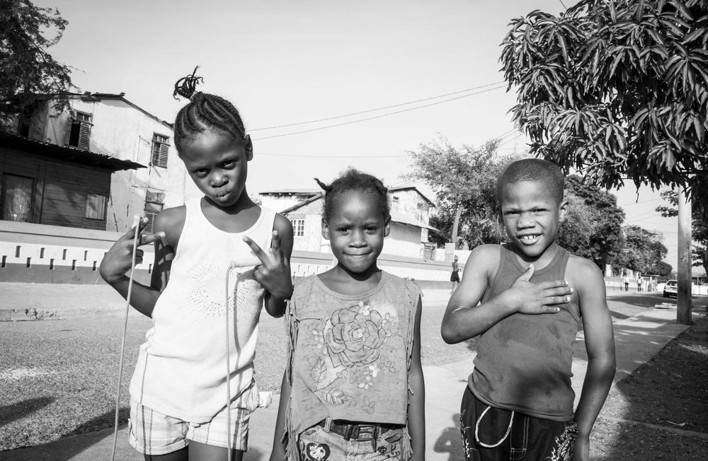 Black and white photograph of children playing outdoors in a casual street scene.