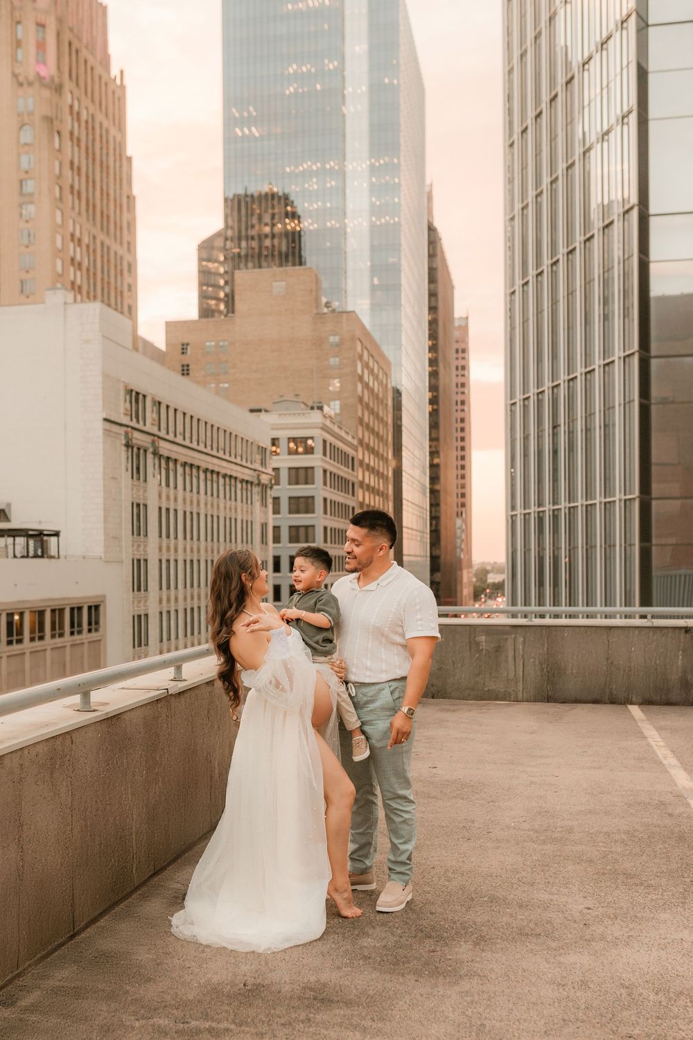 A rooftop maternity session with modern city architecture in the background.