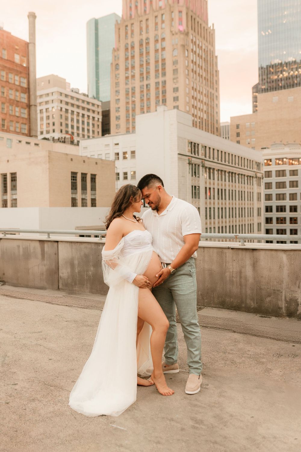 A romantic maternity photoshoot on a city rooftop with art deco buildings in the background.
