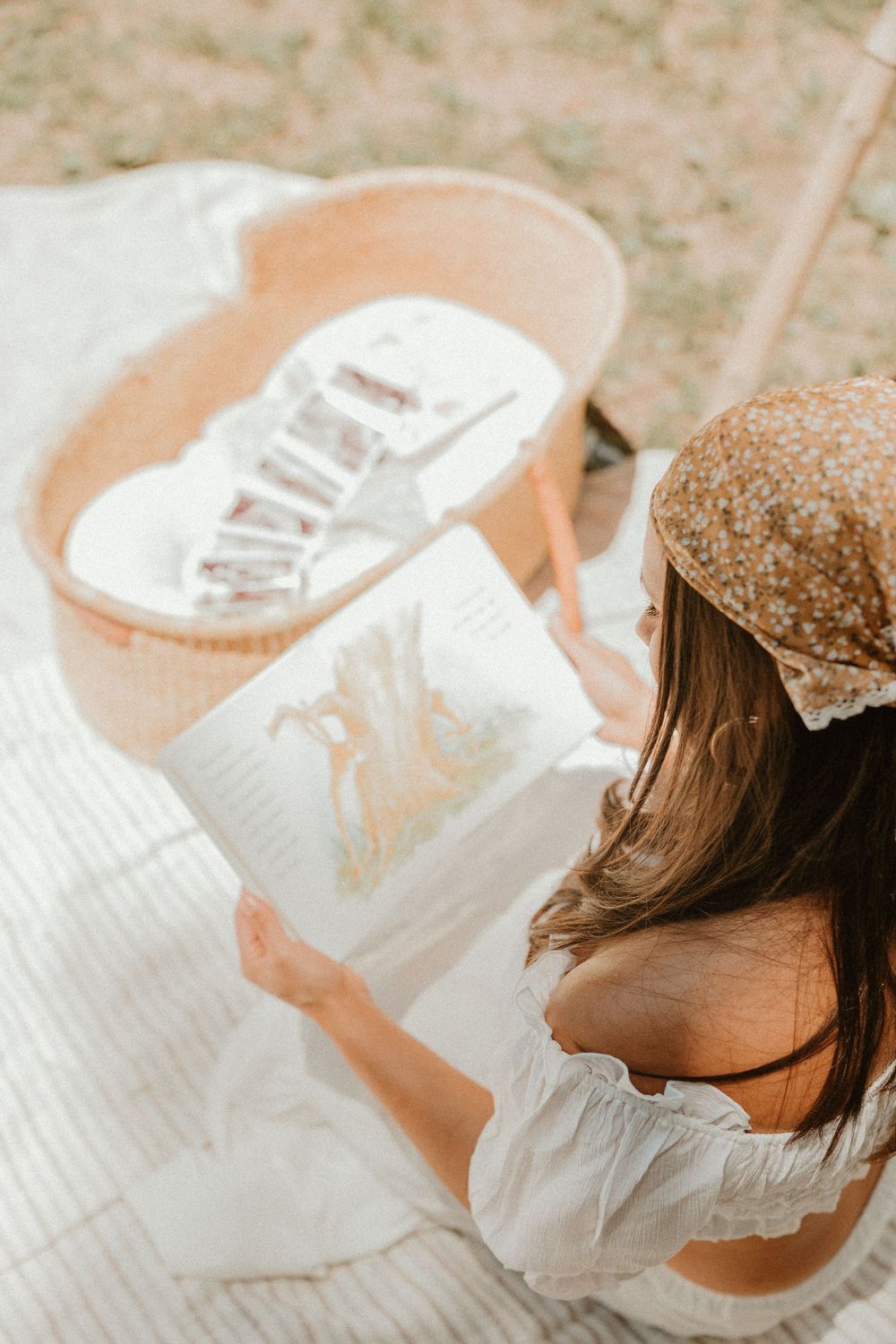 Person in white dress and brown hat reading from white paper, captured from above in dreamy vintage style.