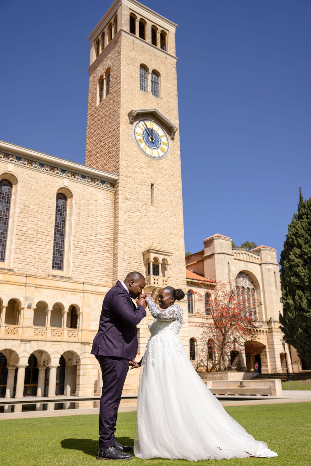 A romantic wedding photo sequence captured on the grounds of a beautiful stone church with arched windows and clock tower.