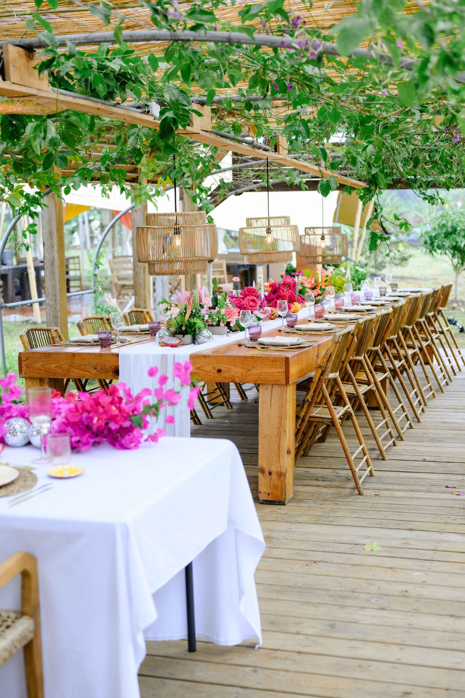 A la Ferme Anarcadier en Guadeloupe une immense table de mariage romantique avec un centre de table composée de fleurs.