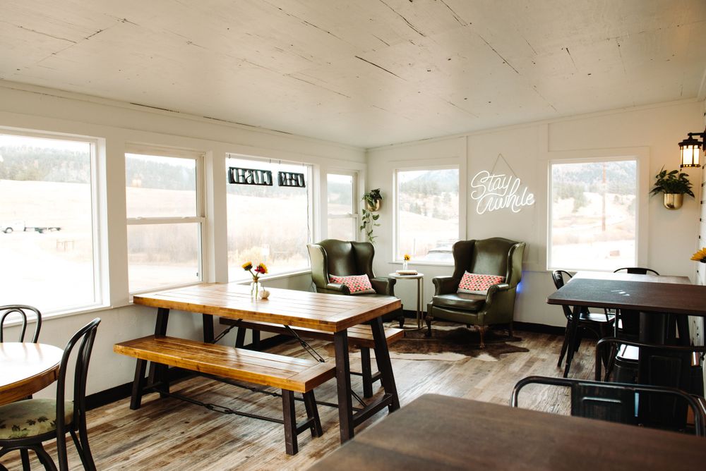 Bright sunlit cafe interior with wooden tables, benches and modern rustic decor.