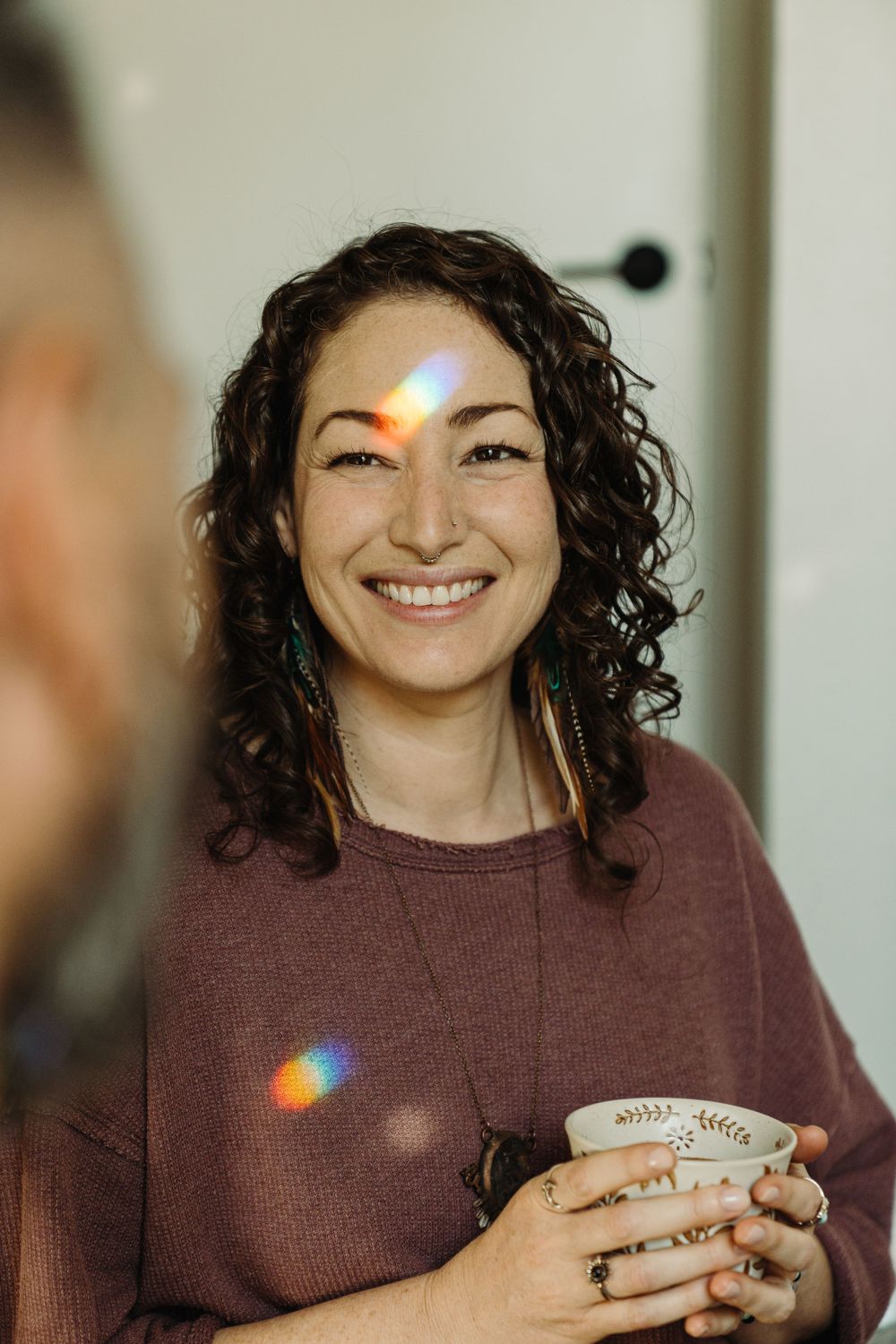 Person holding coffee cup with lens flare effect in natural window light.