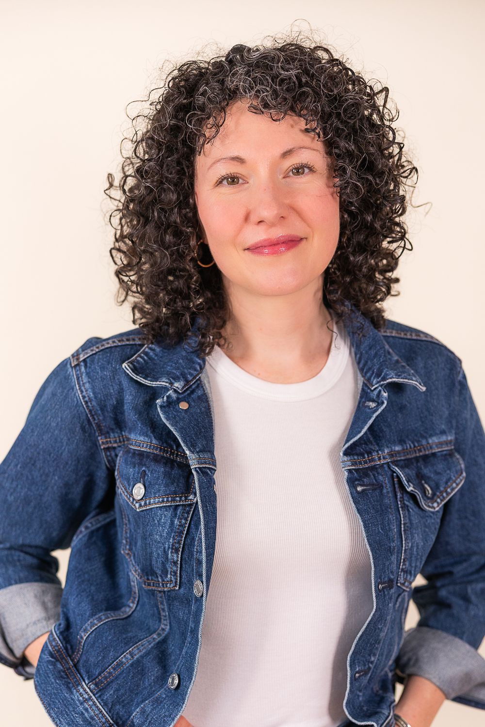 Person in denim jacket and white top poses playfully against light background in four similar shots.