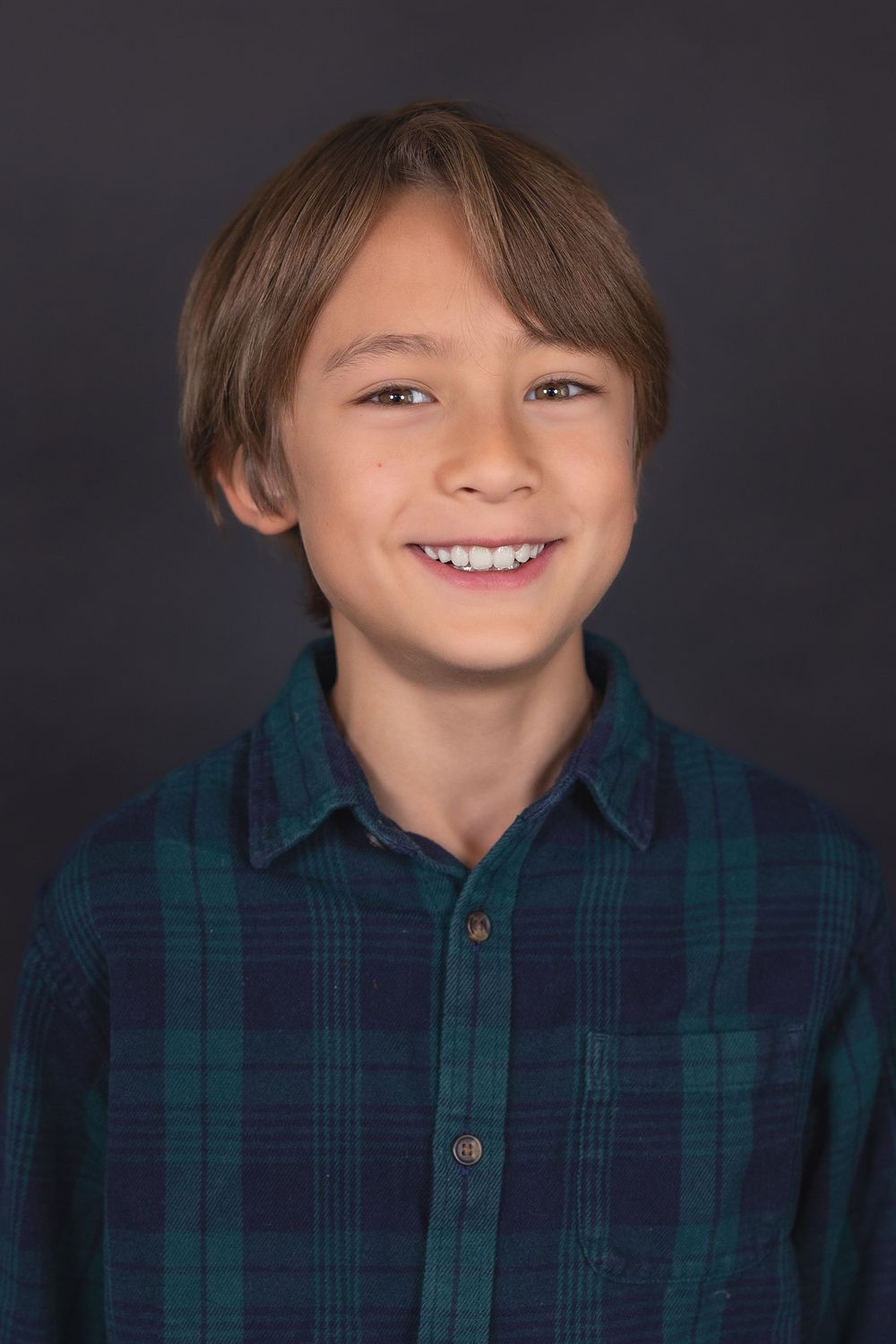A series of four headshots showing someone in a blue and green plaid shirt against a dark background.