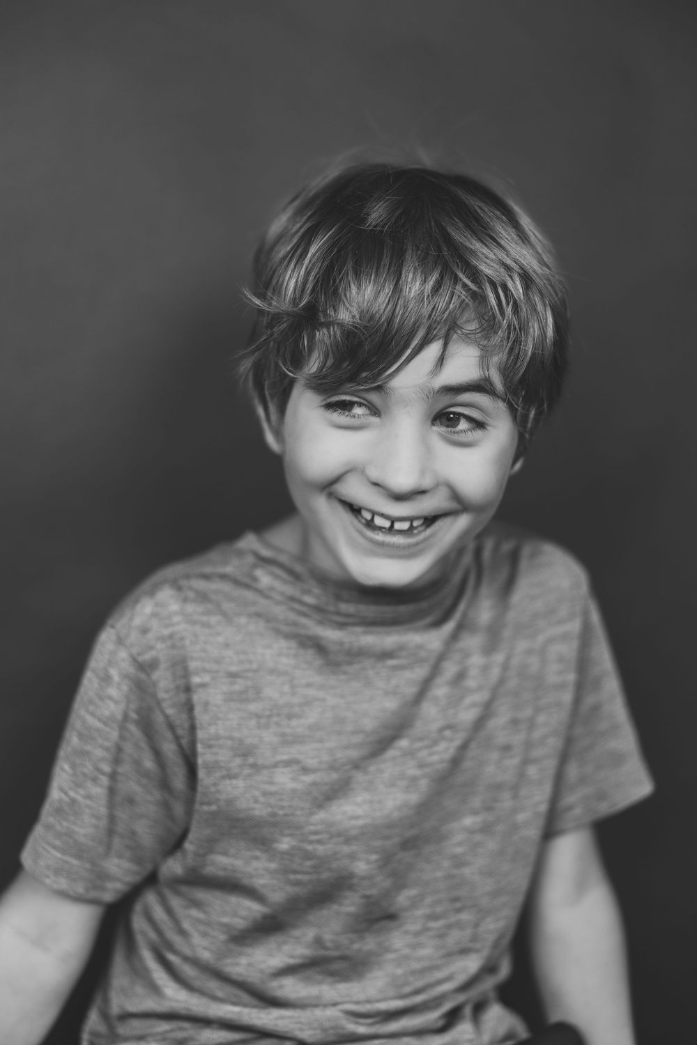 A series of black and white portraits showing expressions of joy and laughter in a gray t-shirt.