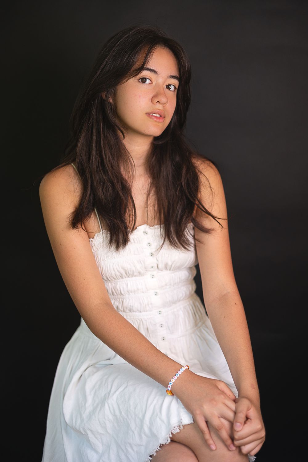 A portrait in a white dress against a dark background showcasing contemplative styling.