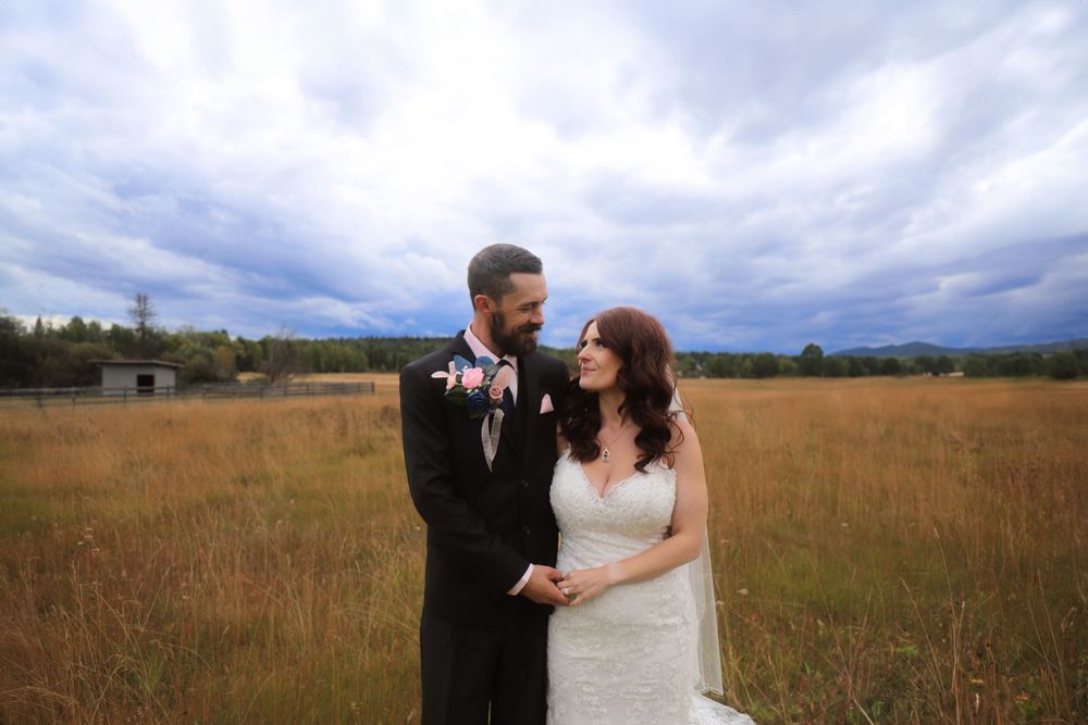 Wedding couple embraces in an autumn field with stormy clouds overhead.