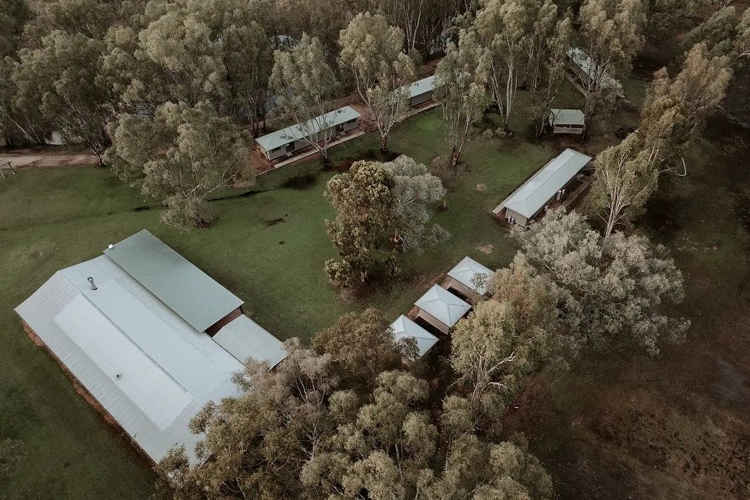 Aerial view of rural property with white storage buildings and trailers surrounded by autumn trees.