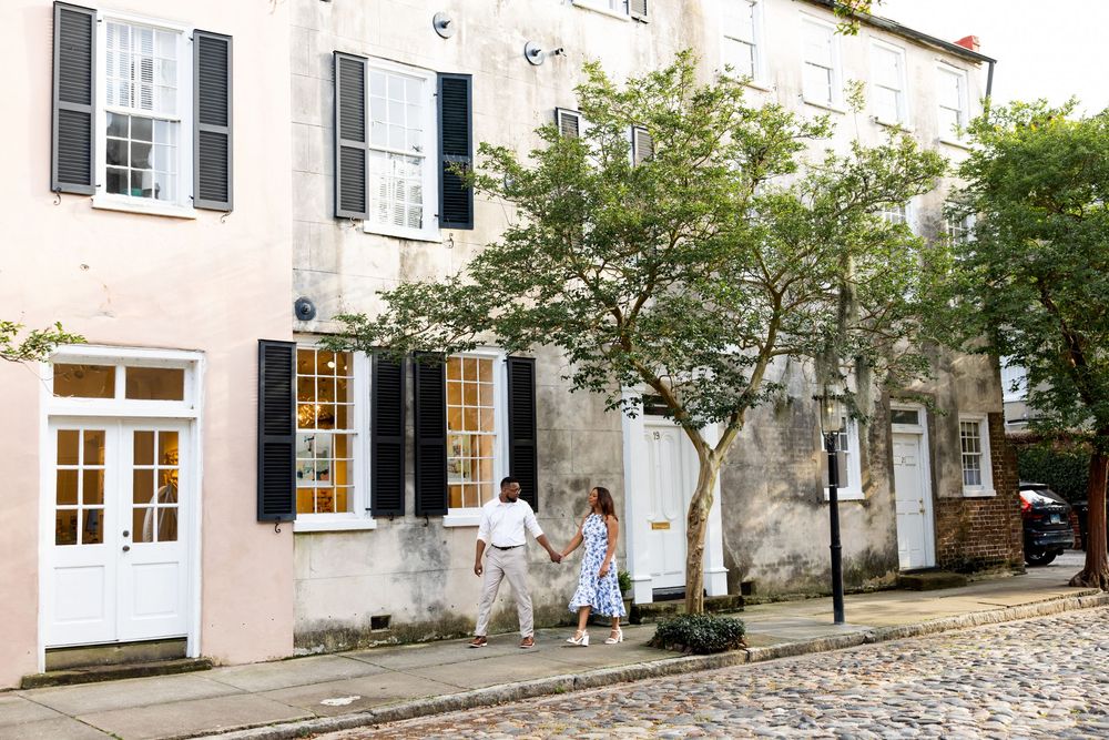 A charming cobblestone street with traditional European buildings and trees creating a peaceful urban scene.