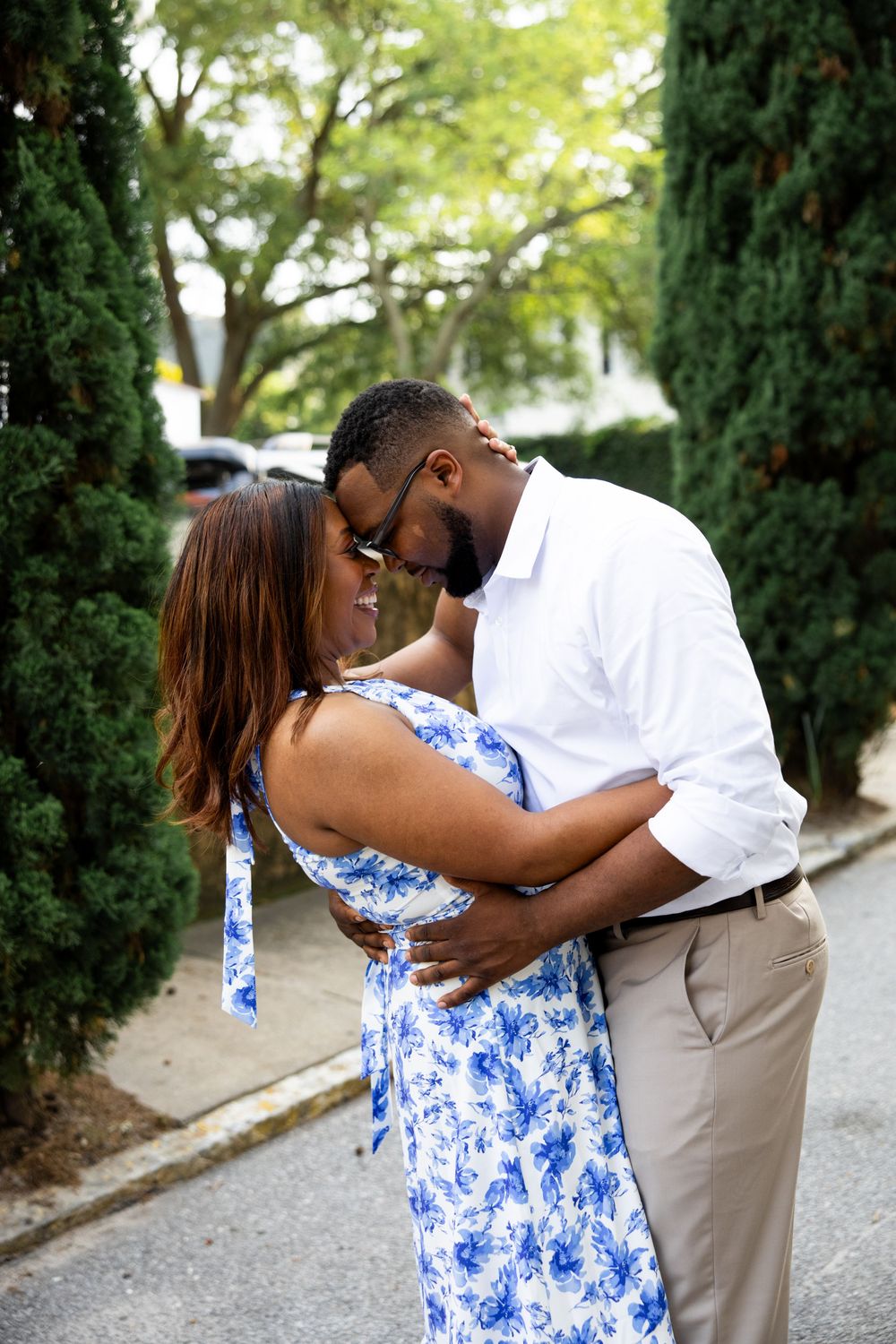 A couple in coordinating blue and white outfits shares playful moments during an outdoor photoshoot.