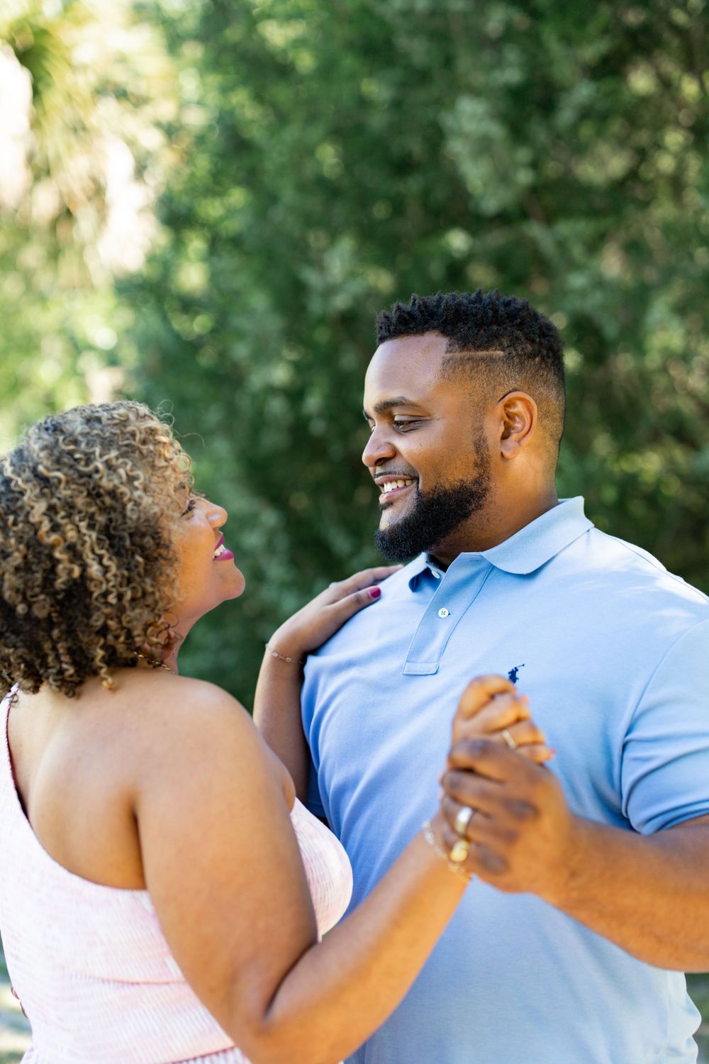 A couple shares a joyful dance moment together in a garden setting with Spanish moss in the background.