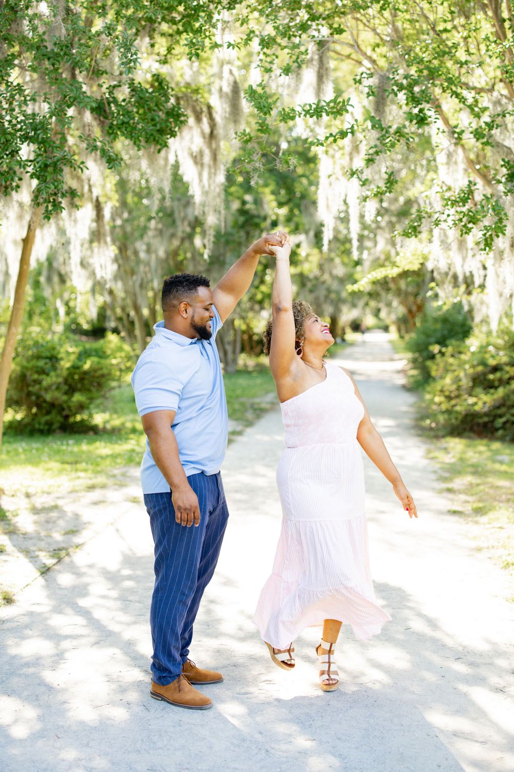 A dancing couple twirls together on a tree-lined path.