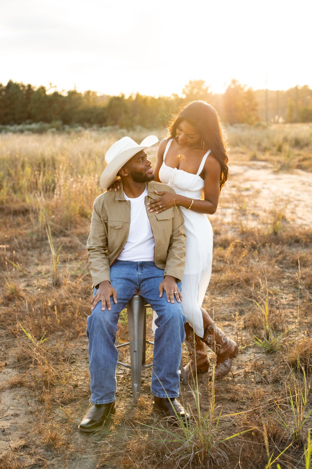 A romantic outdoor photo shoot in a grassy field at golden hour sunset.
