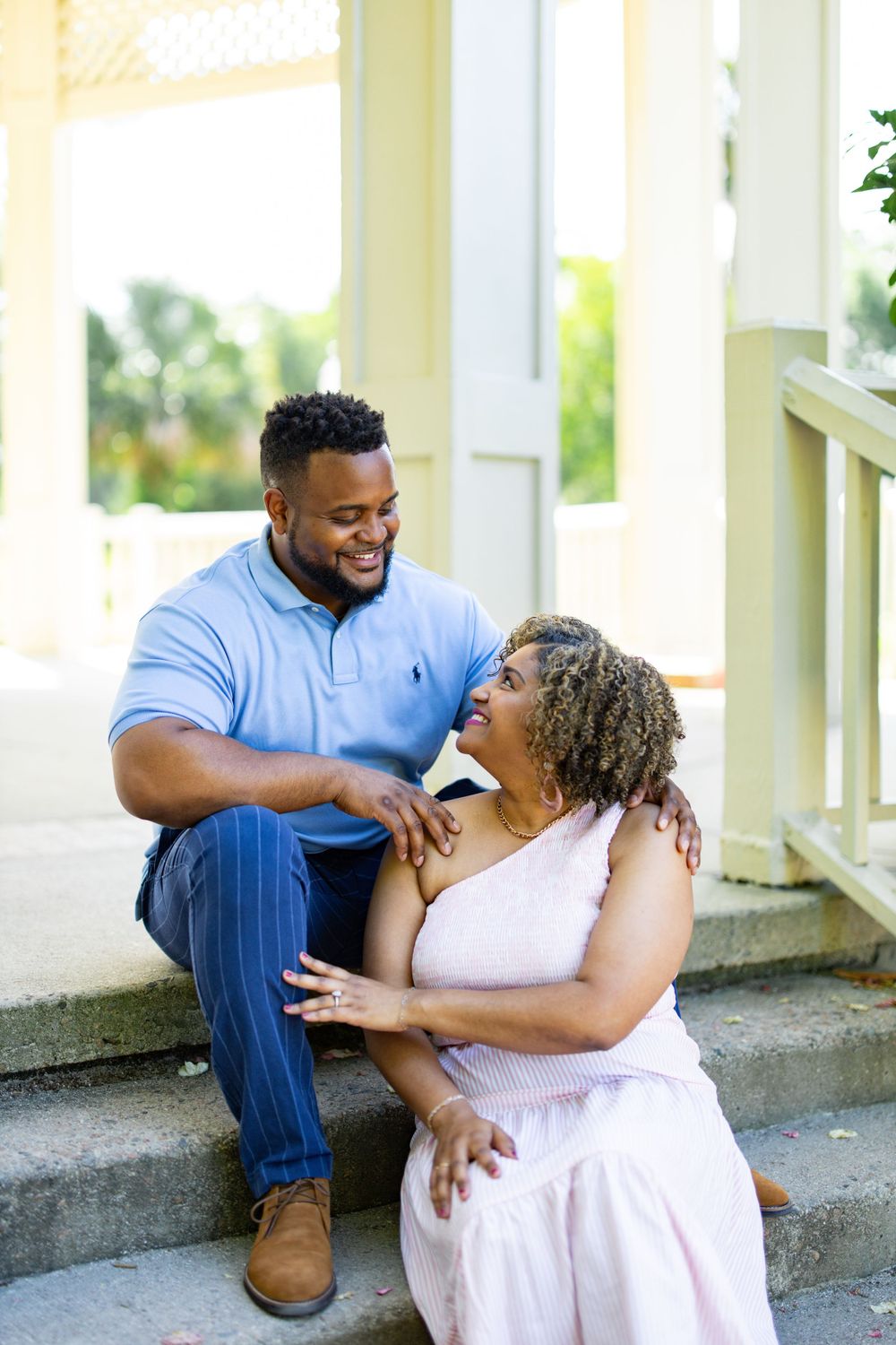 A couple shares a joyful moment while sitting on concrete steps outdoors.