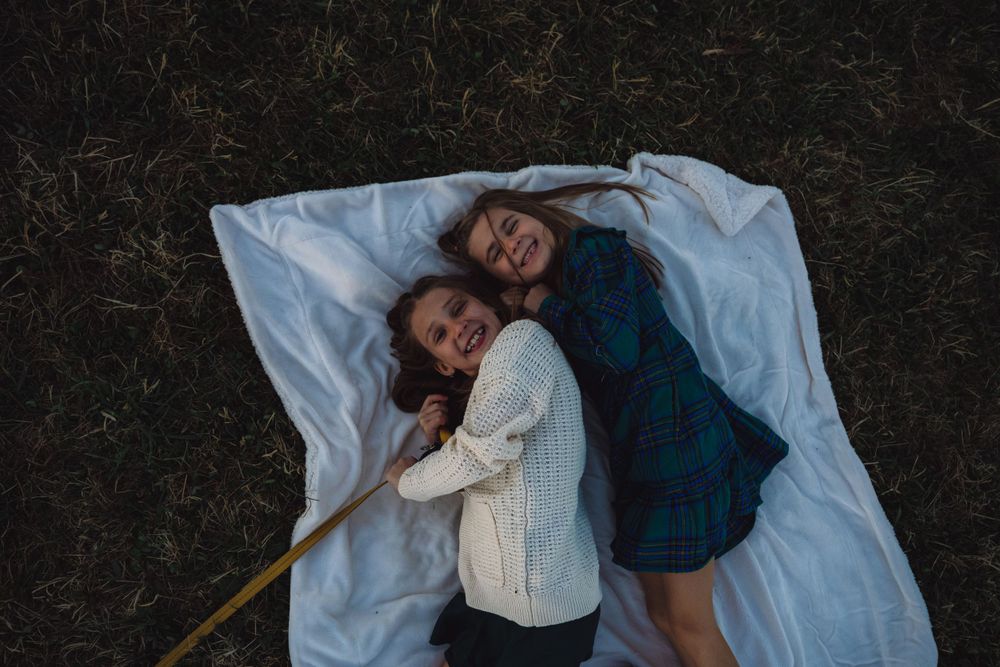 Couple lying on white blanket during outdoor photo session.