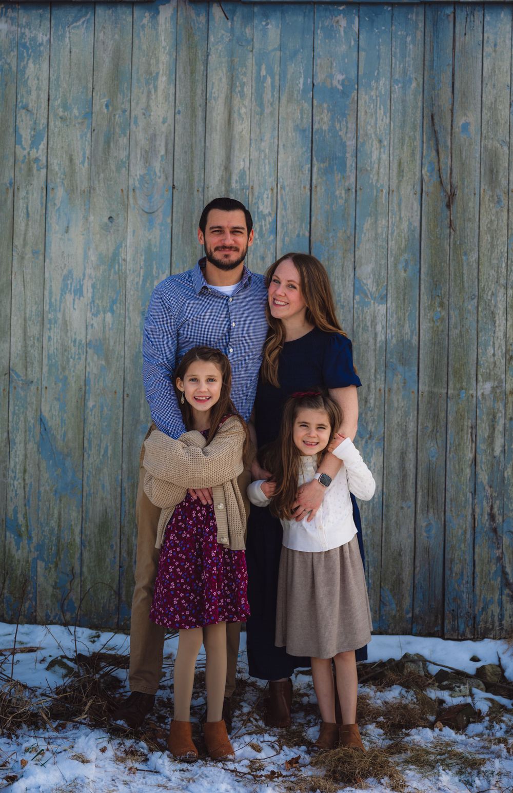 Family group photo session against rustic blue wooden wall background.