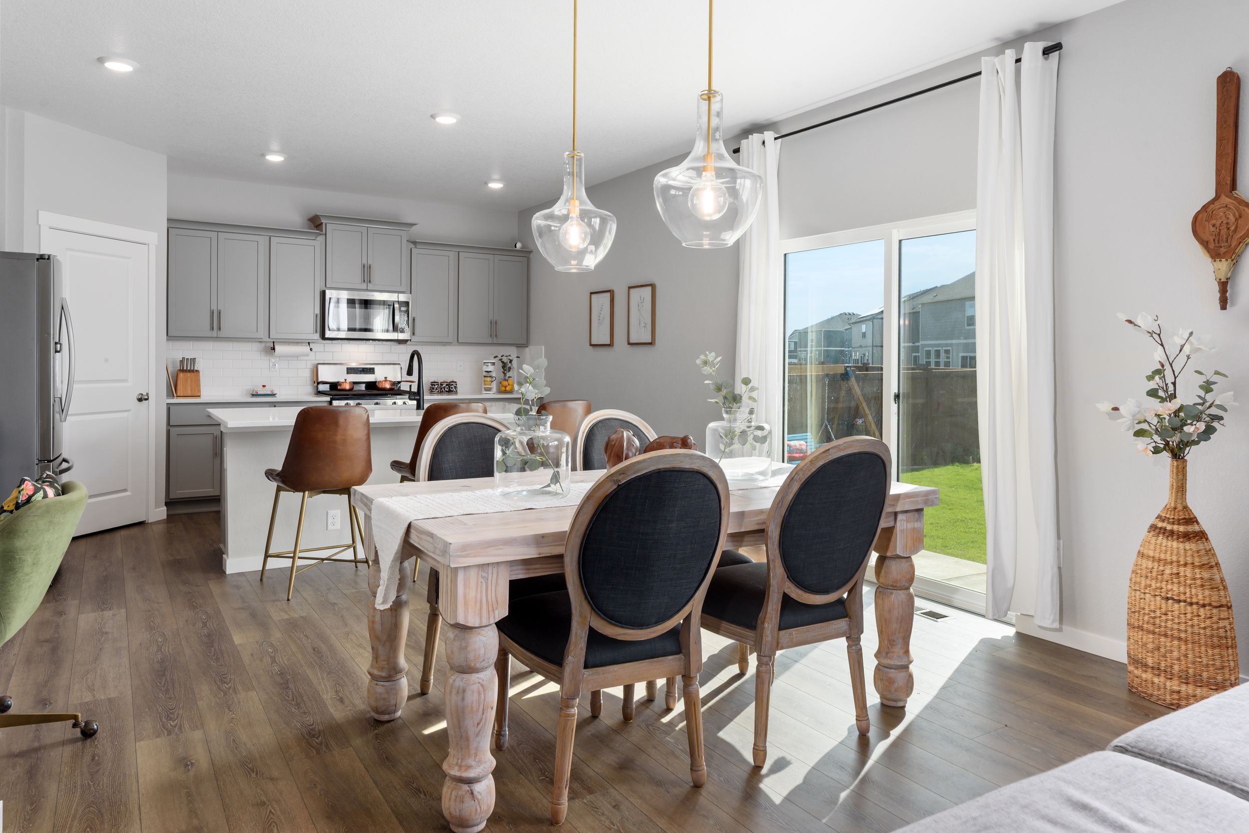 Modern open concept home interior with light gray walls, hardwood floors and pendant lighting throughout the space.
