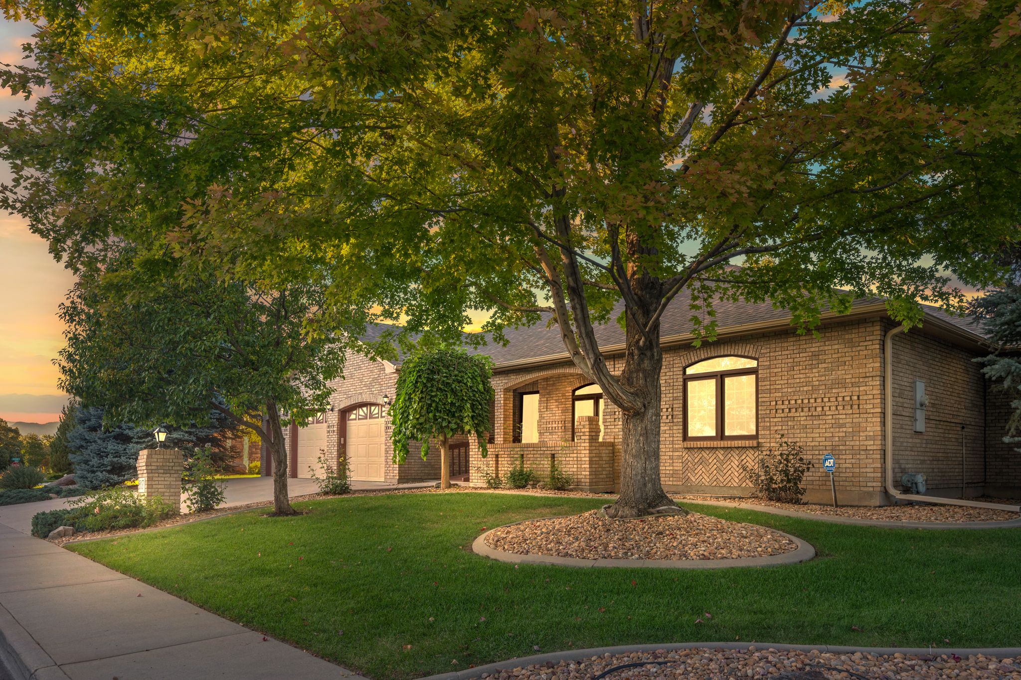 Exterior view of a modern brick home with large windows and landscaped yard at dusk.