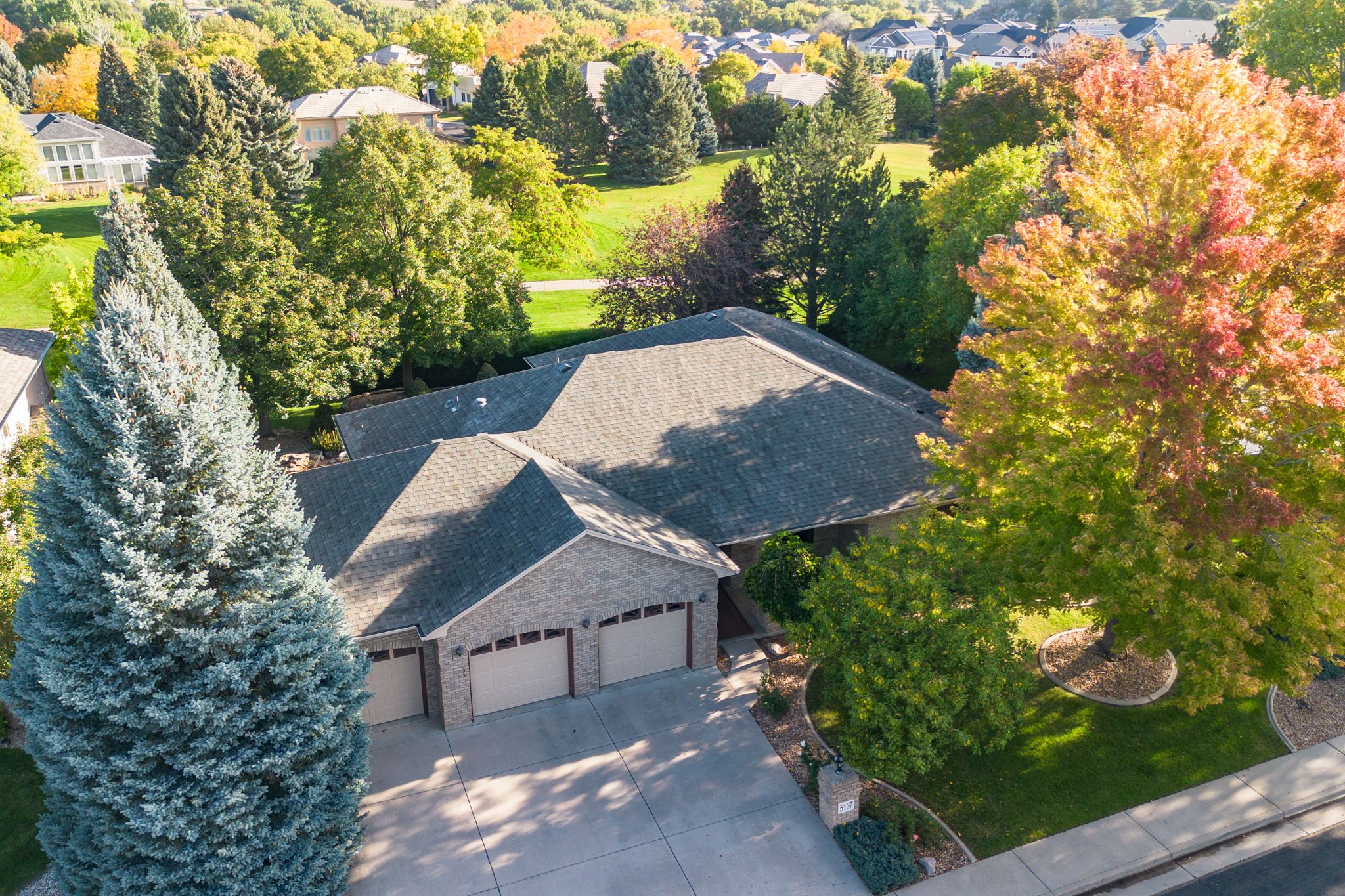 Aerial drone view of a residential neighborhood with colorful autumn trees and houses during fall season.