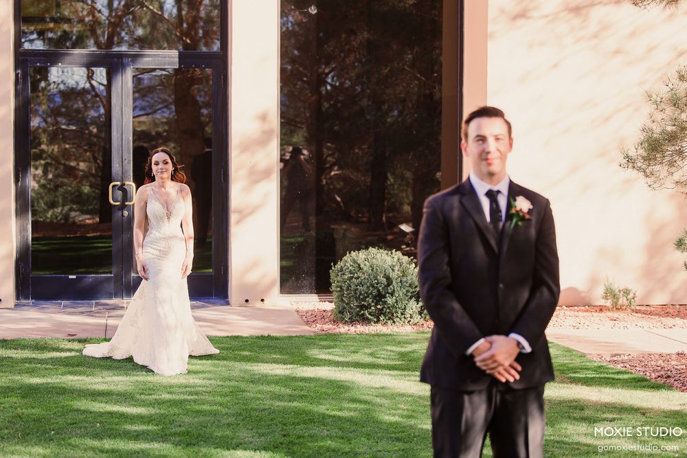 Wedding couple meeting in an outdoor garden venue with rustic stone walls and landscaping.