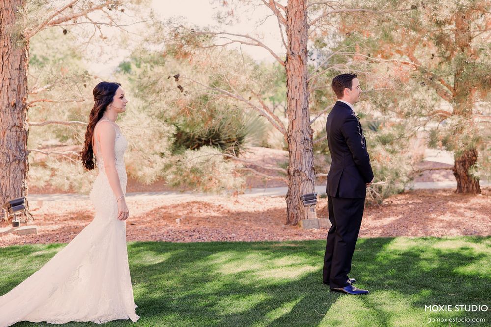 A couple shares a romantic first look moment in a garden setting with natural stone walls and greenery.