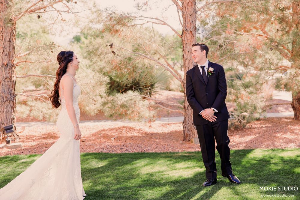 A romantic wedding couple poses in a lush garden setting with soft pink tones and natural greenery.