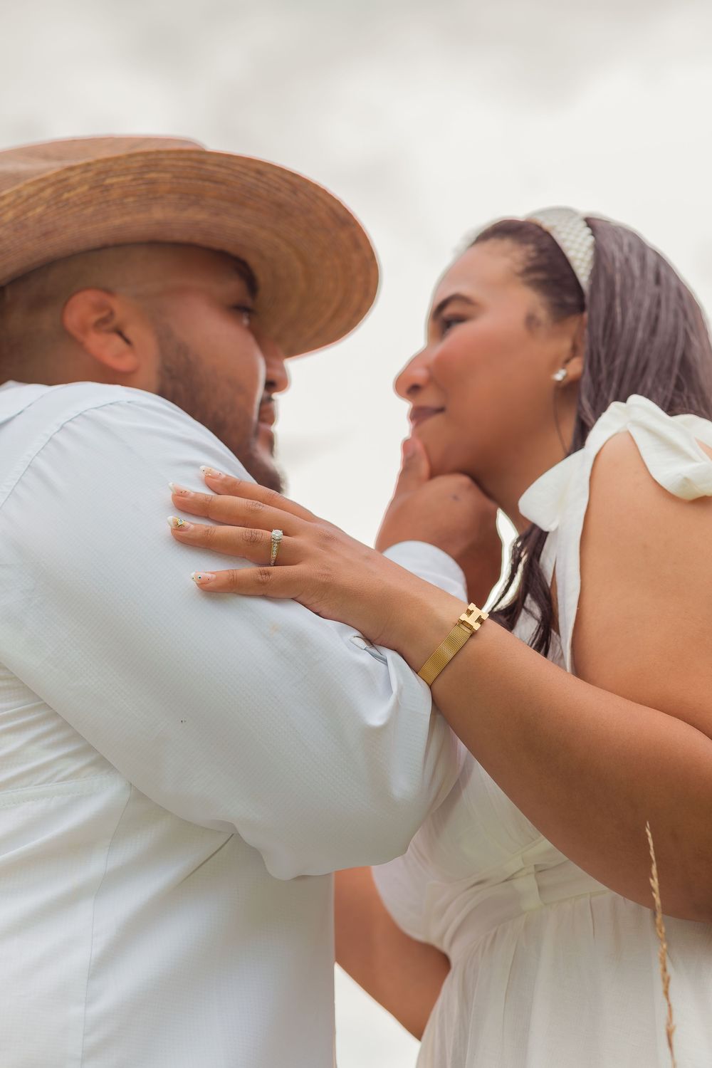 A romantic sequence of a couple in white clothing and cowboy hat sharing tender kisses on a bright sunny day.