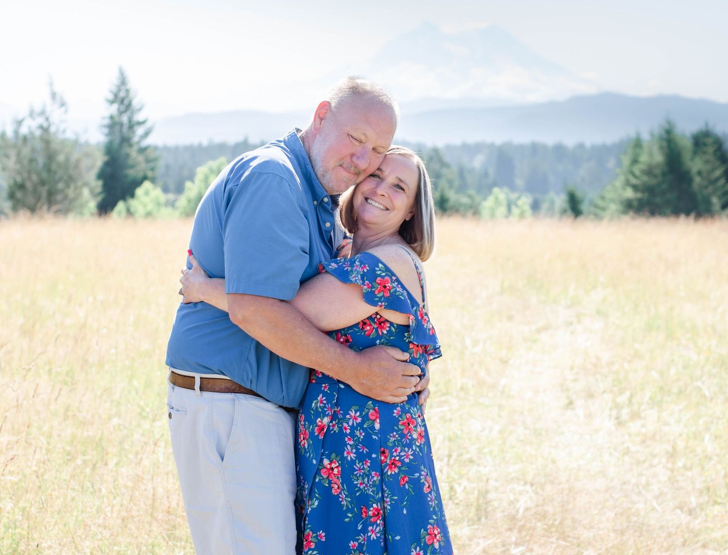 Tender embrace captured during a summer couples session in a mountain field.