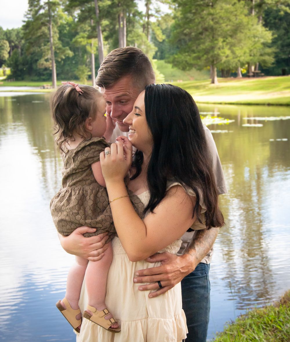 Romantic couple embraces by a serene lake during a photo session in a park setting during family photos.