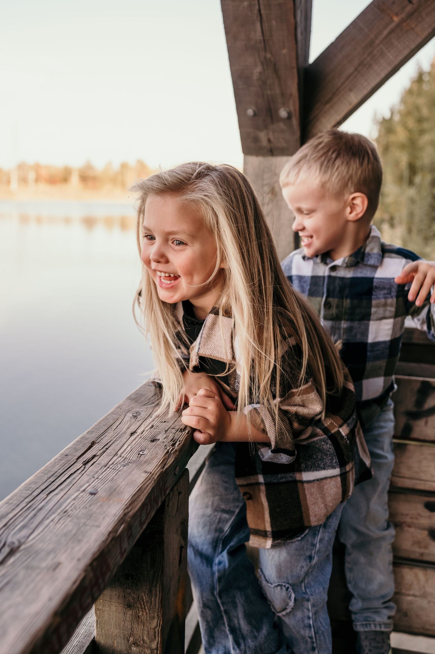 Two children share a sweet moment together while sitting on a rustic wooden bench outdoors.