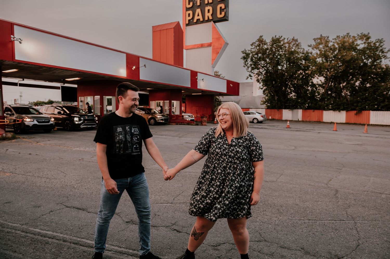 Playful couple having fun in retro-style parking lot with vintage signage.