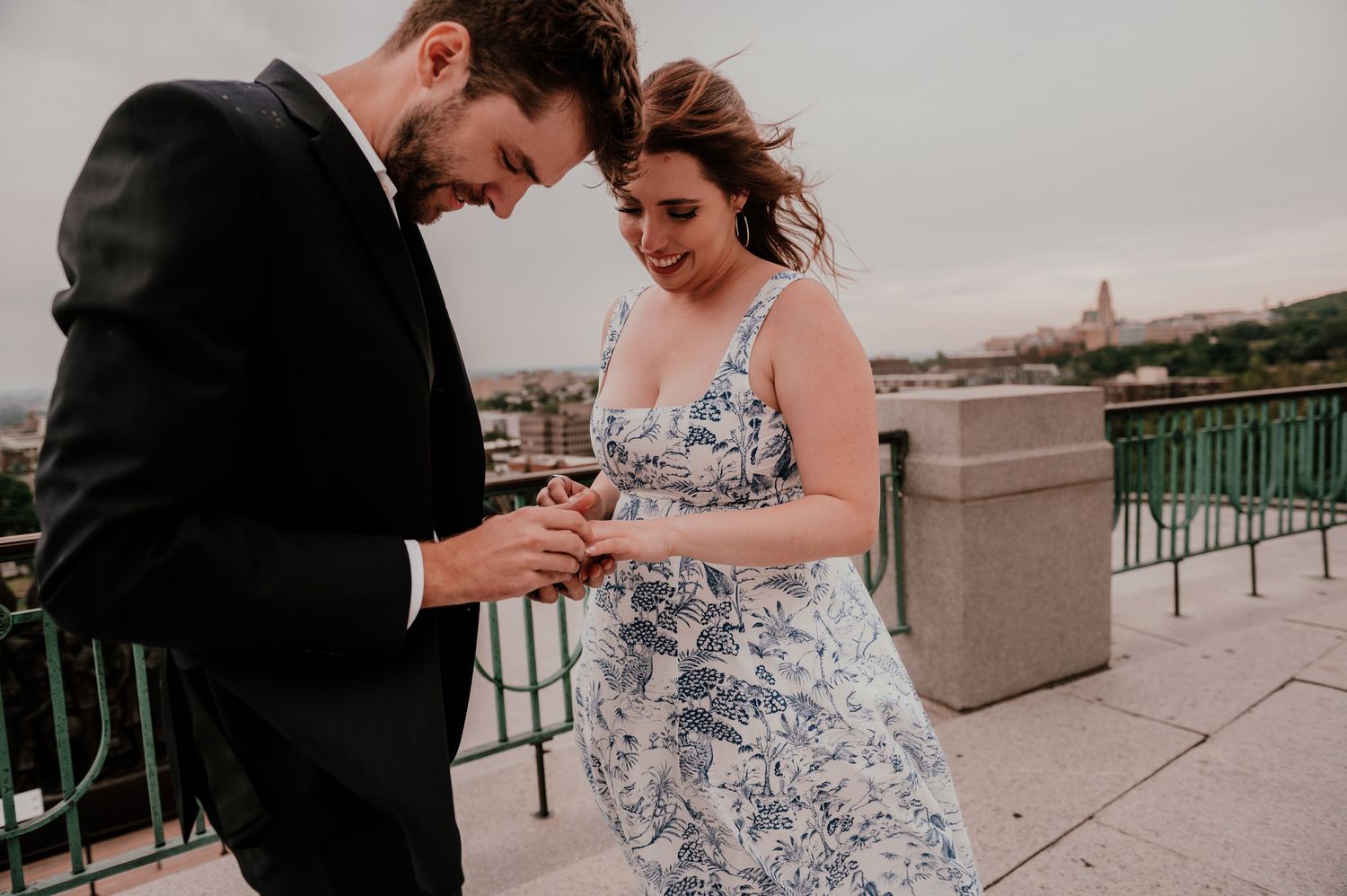 A romantic moment captured on an urban rooftop as a couple looks at something together.