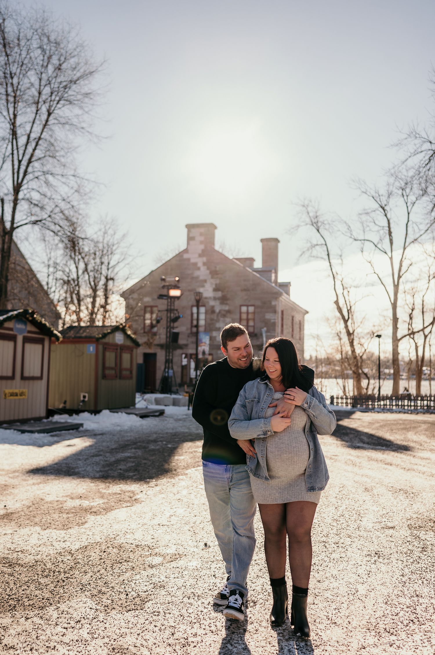 A couple shares an intimate moment in front of a historic building on a snowy winter day.